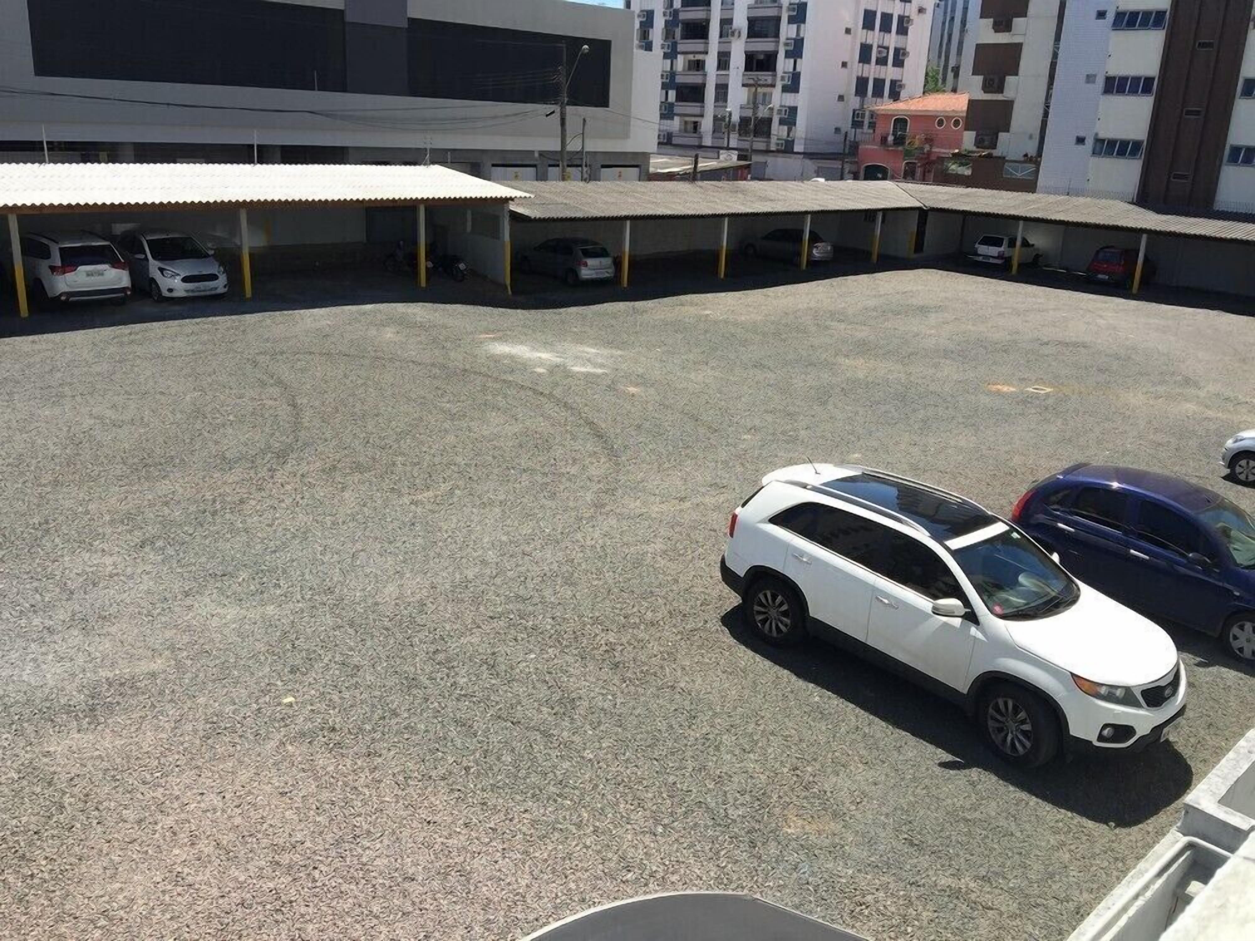 A parking lot with several cars, including a white SUV and a blue sedan.