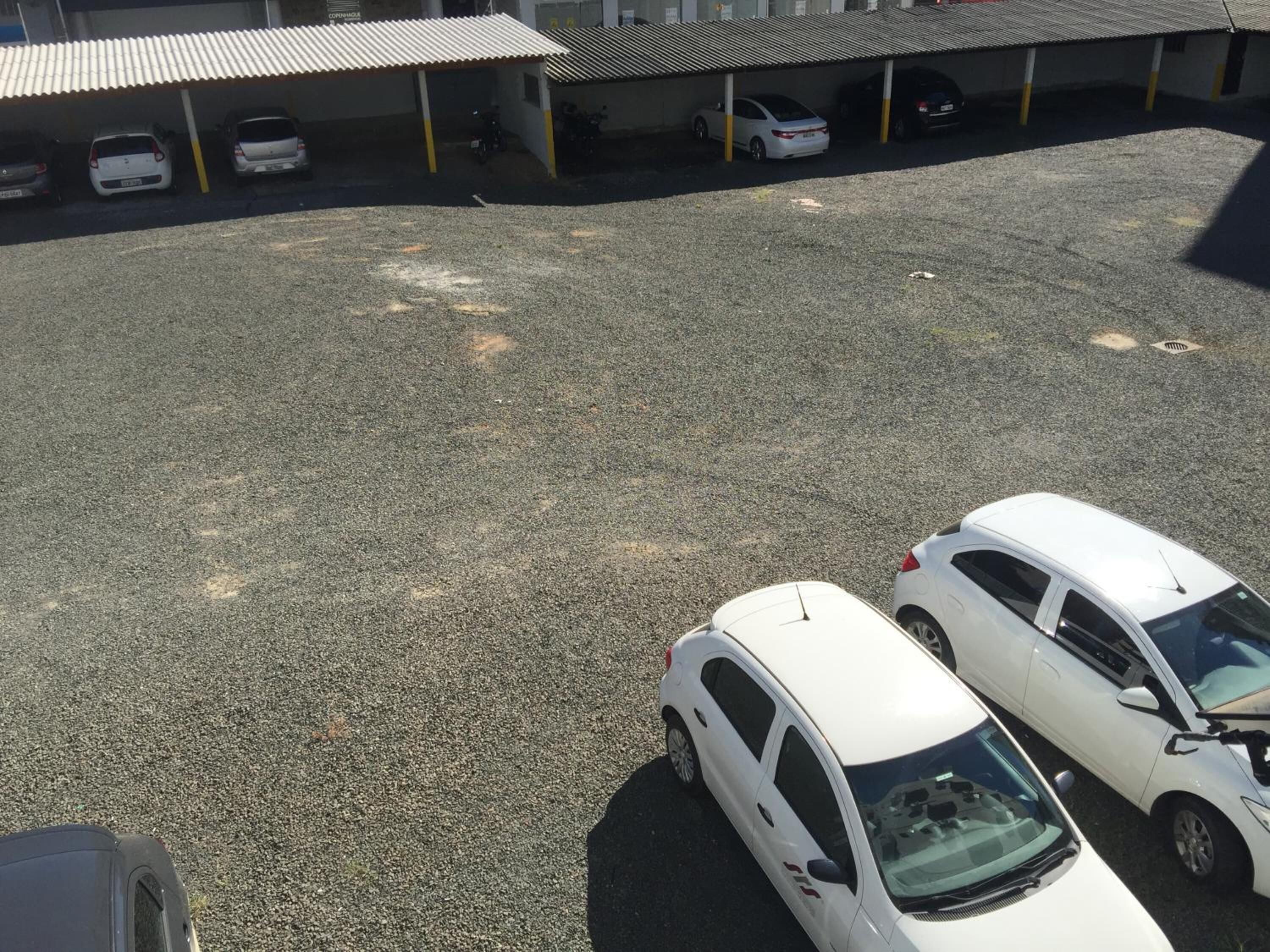 A parking lot with several white cars parked under a covered area.