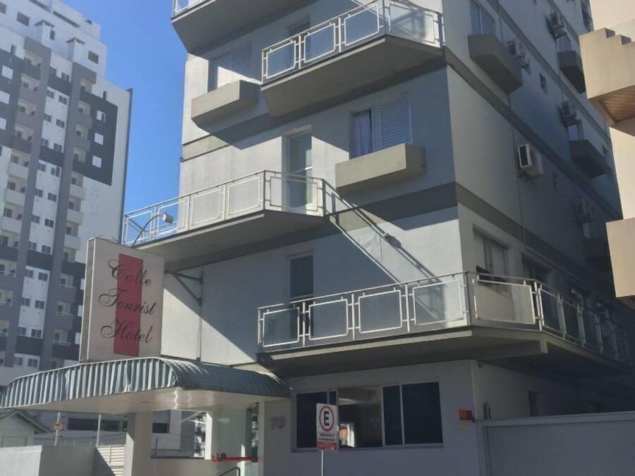 A multi-story hotel with balconies, a sign for the "Folle Tourist Hotel," and a no parking sign.