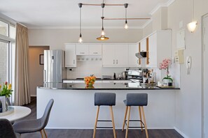 Une cuisine moderne dotée d’un îlot central, de tabourets de bar et de luminaires suspendus.