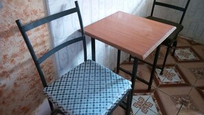 A small room with a checkered chair, a wooden table, and patterned tiles on the floor. - Haricot Guest House (Murang'a)