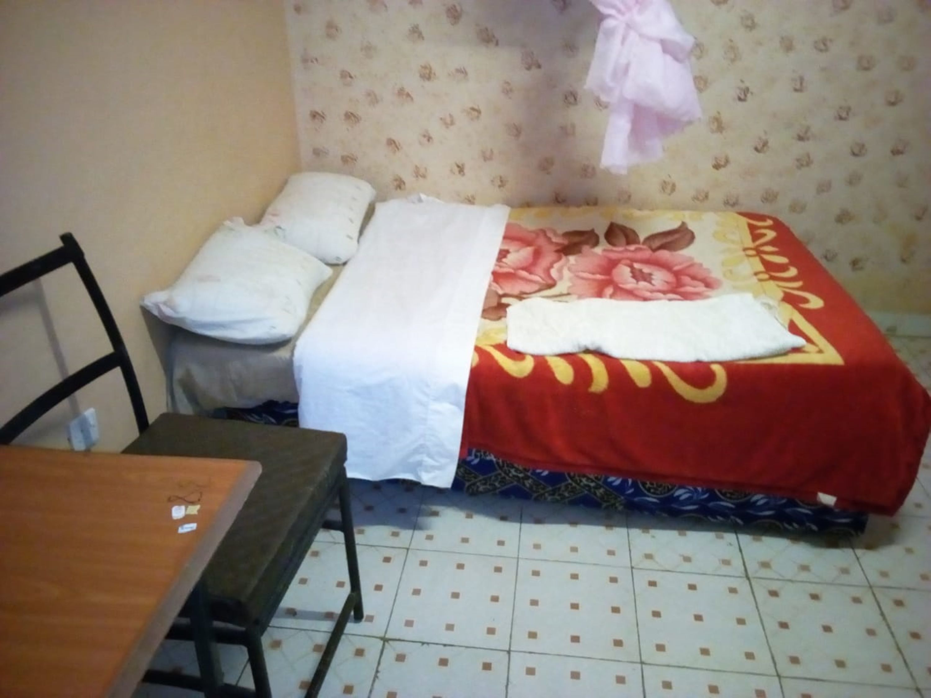 Une petite pièce avec un lit, une chaise et une table.