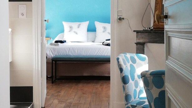 Un dormitorio con cama, una silla y pared azul.
