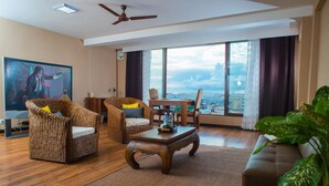 Ein modernes Wohnzimmer mit Korbmöbeln, einem Holztisch und einem großen Fenster mit Blick auf die Stadt.