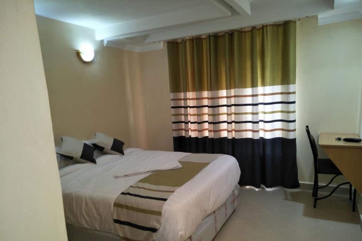 A hotel room with a bed, a desk, and a chair.