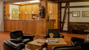 Un hall acogedor con paneles de madera, sillones de cuero, un mostrador de recepción y una estatua.