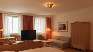 Una habitación de hotel con una cama, un escritorio con computadora, televisor, sofá y armario.