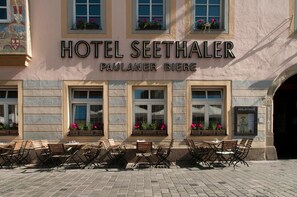 El exterior del Hotel Seethaler, con fachada tradicional, amplias ventanas con jardineras y zona de estar al aire libre.
