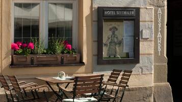 Ein Außenbereich mit Tischen und Stühlen vor einem Gebäude, an dem ein Schild mit der Aufschrift 'HOTEL SEETHALER' zu sehen ist.