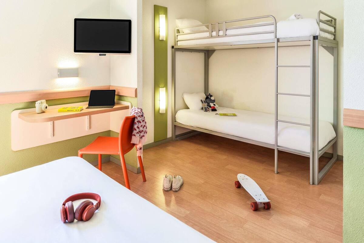 Habitación con literas, un escritorio, una silla y un monopatín en el suelo.