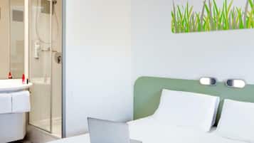 Relax in a serene space with a comfortable bed, glass-enclosed shower, and convenient bedside table.