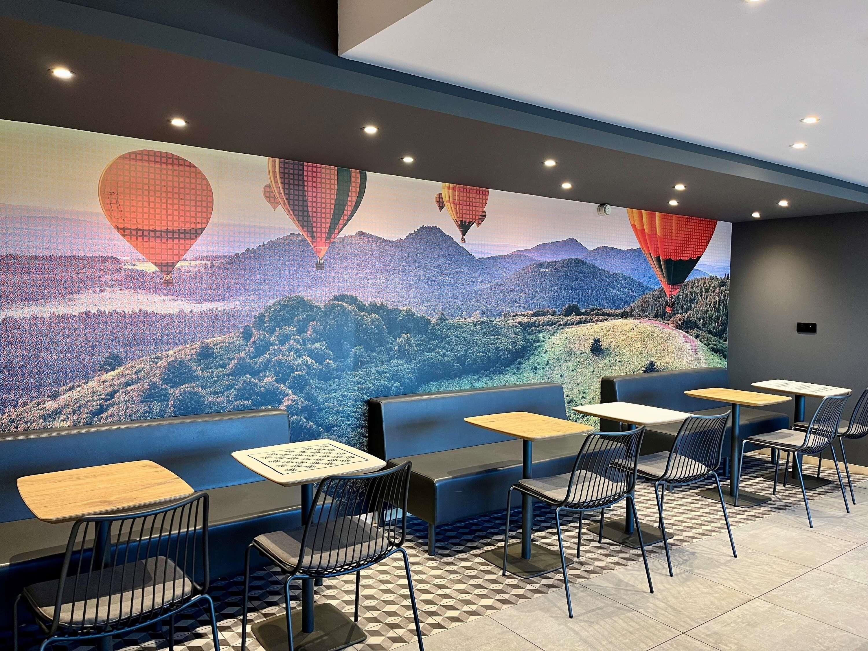A restaurant with a mural of hot air balloons, tables, and chairs.