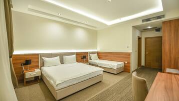 A hotel room with two beds, a desk, a chair, and a wooden wardrobe.