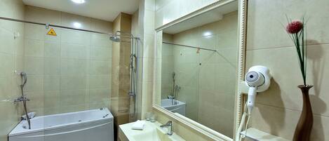 Un baño moderno con bañera, un espejo grande, un lavabo y un secador de pelo.