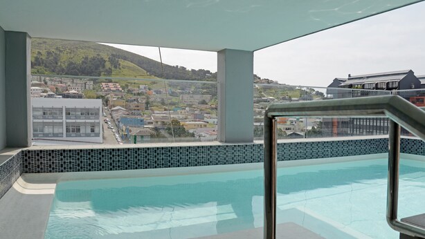 A pool area with a view of a town and hills in the background. - Zara By Stay Amazing (Cape Town)