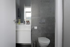 A modern bathroom with a white sink, mirror, and toilet.
