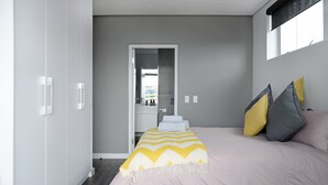 A modern bedroom with a large bed, a wardrobe, and a mirror. - Zara By Stay Amazing (Cape Town)