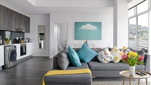 A modern living room with a grey sofa, a yellow throw, and a vase of flowers. - Zara By Stay Amazing (Cape Town)