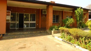 A building with a brick facade, large windows, and a covered entrance. - Sharon's Guest House (Lusaka)
