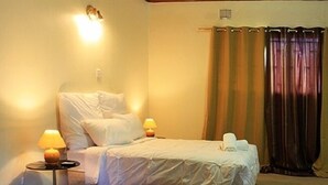 A single bed with white bedding, two bedside lamps, and a curtain. - Sharon's Guest House (Lusaka)