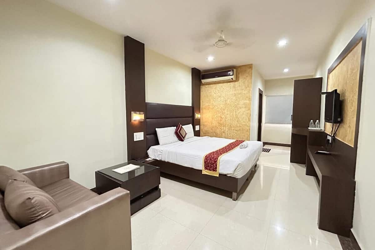 Una habitación de hotel moderna con una cama grande, un sofá, una mesita y un televisor.