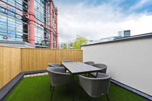 A rooftop patio with a table and chairs, surrounded by a wooden fence and a white wall. - The Seamus Heaney Suite - hiphipstay (Dublin)