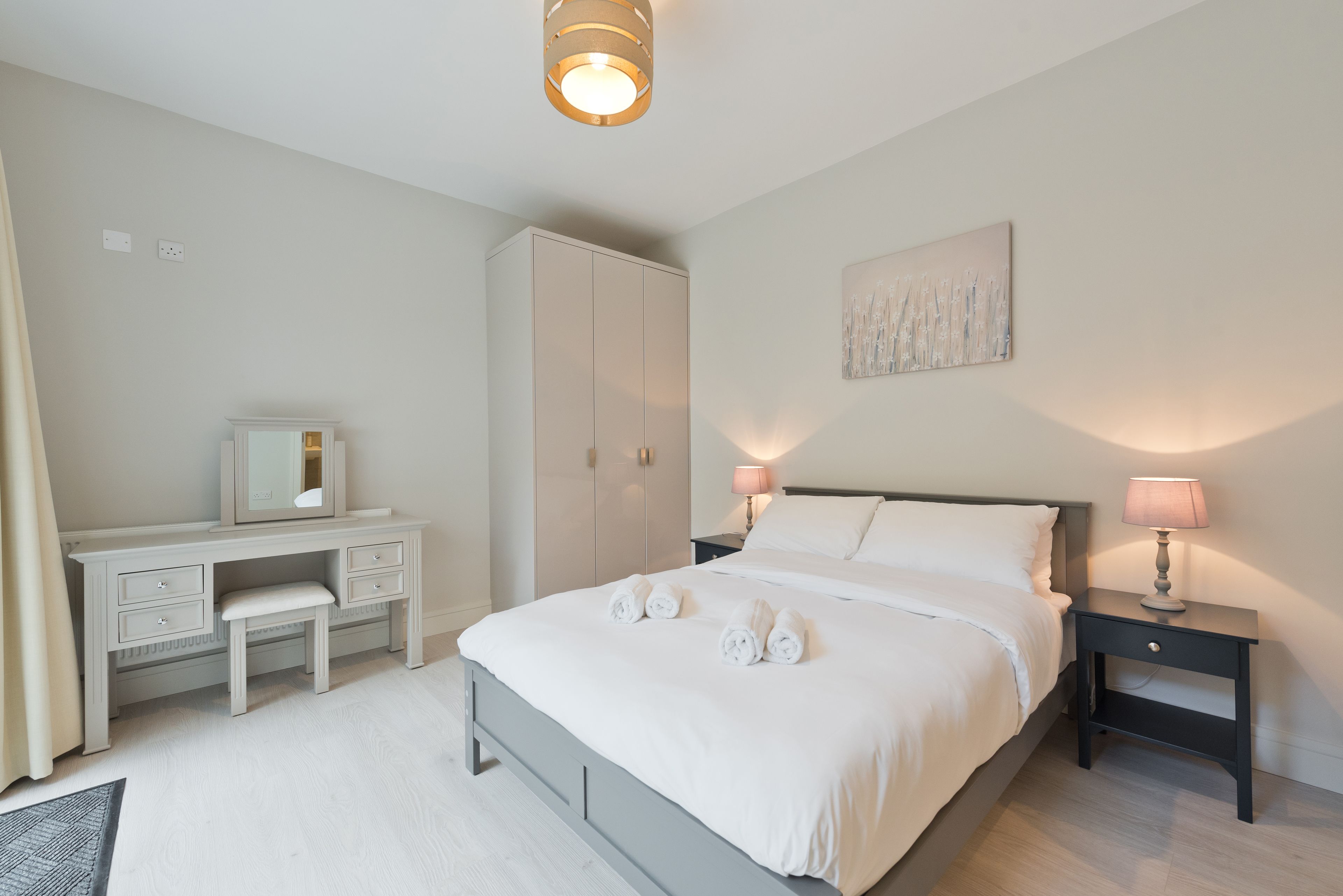 Une chambre à coucher comprenant un lit, des tables de chevet, une commode et une armoire.