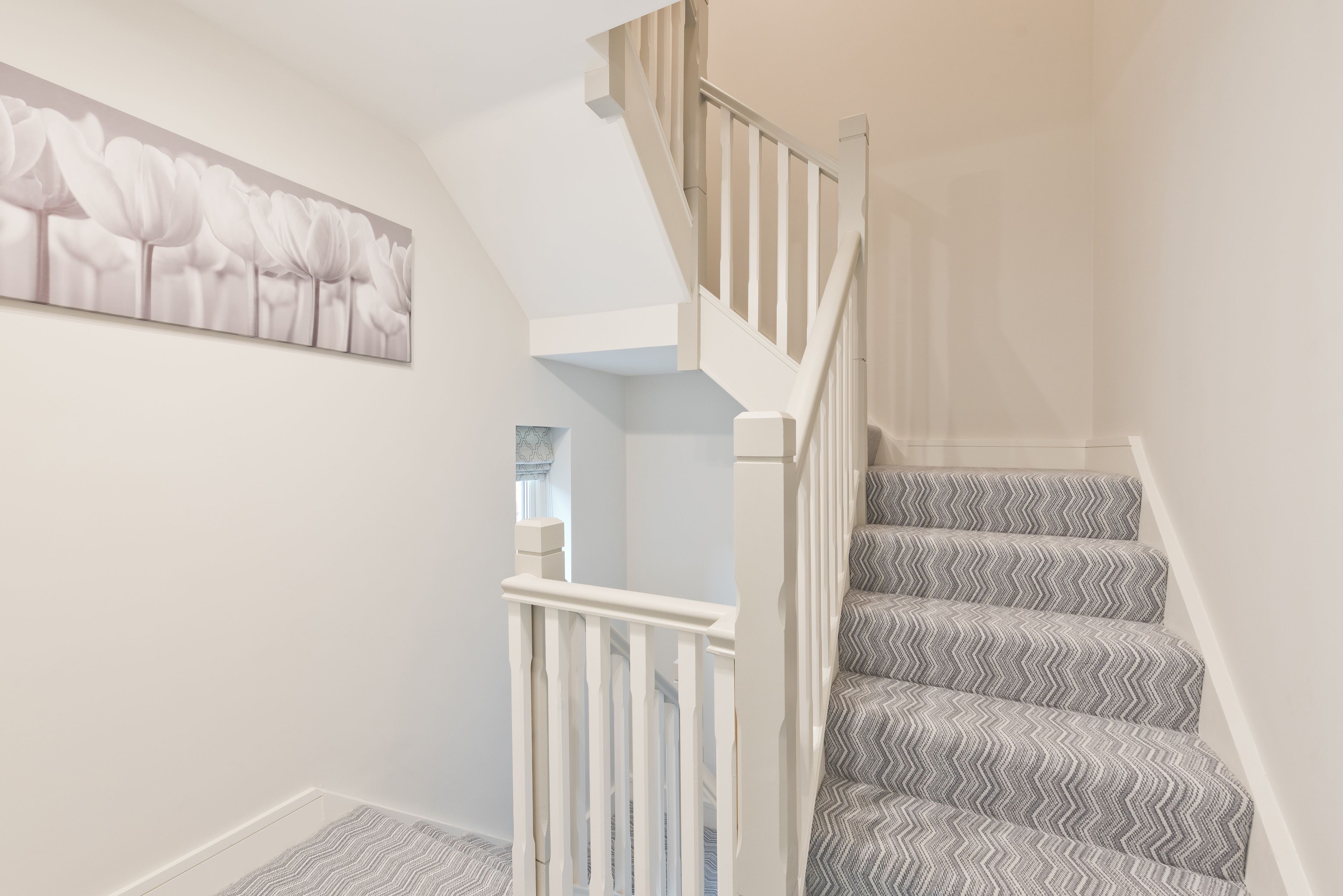 A staircase with a zigzag patterned carpet and a white railing.