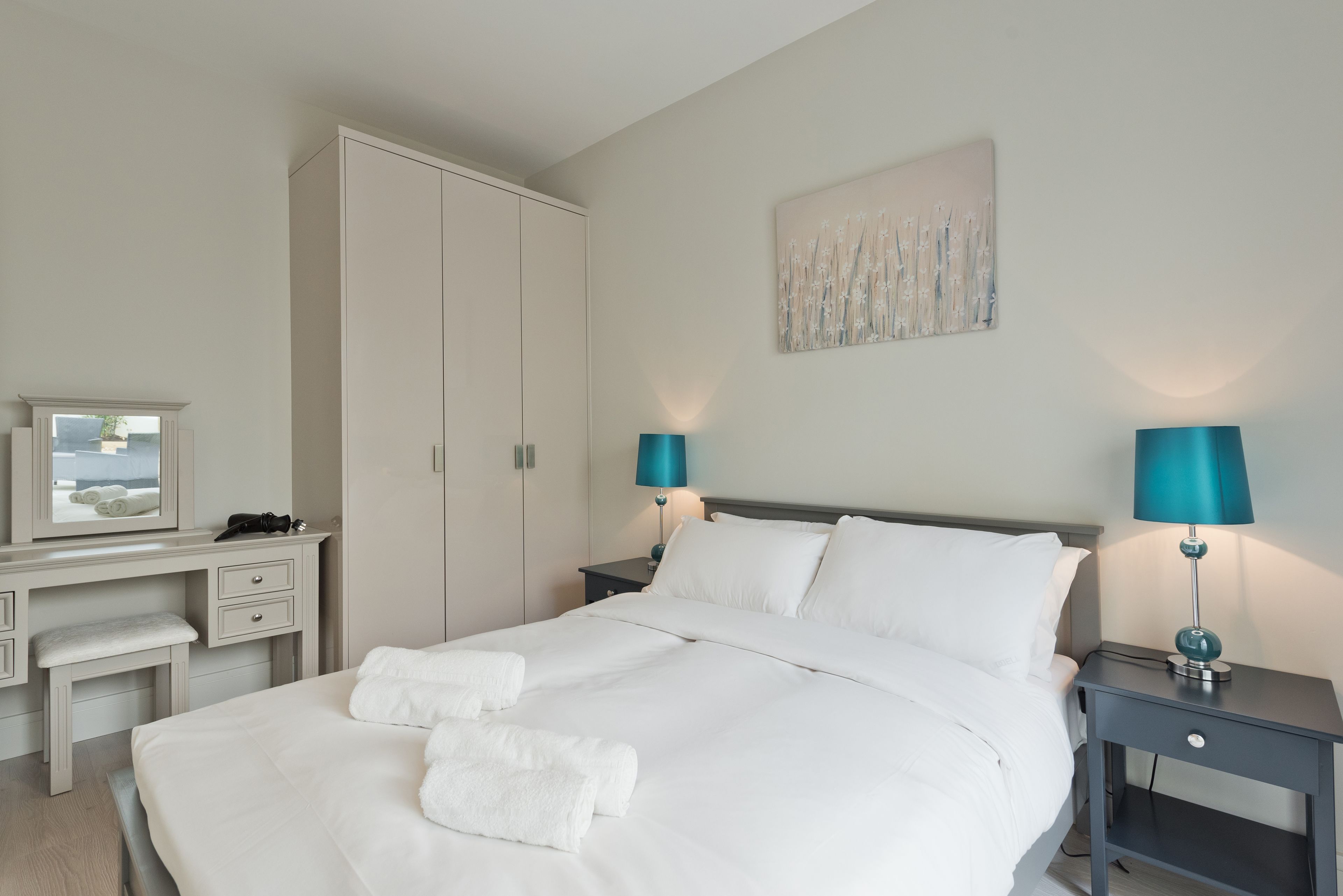 A hotel room with a bed, bedside tables, a desk, and a wardrobe.
