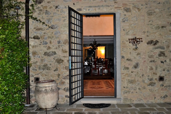 Une entrée en pierre, ornée d’un grand pot, d’une porte et d’un lustre visible à l’intérieur.
