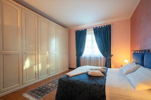 A bedroom with a bed, a nightstand, a lamp, a window with curtains, and a wardrobe. - Pino Villa: Pool, Chianti & Thermal Baths (Gambassi Terme)