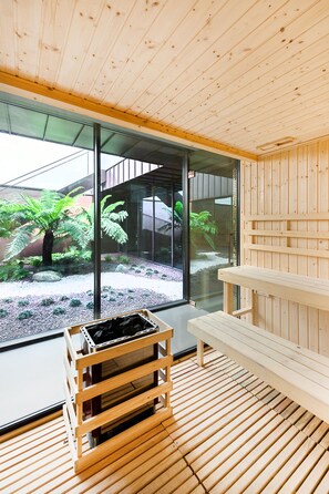 A wooden interior with a bench, a wooden crate, and a glass wall with a view of a garden.
