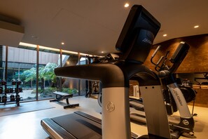 A gym with treadmills, dumbbells, and a bench.