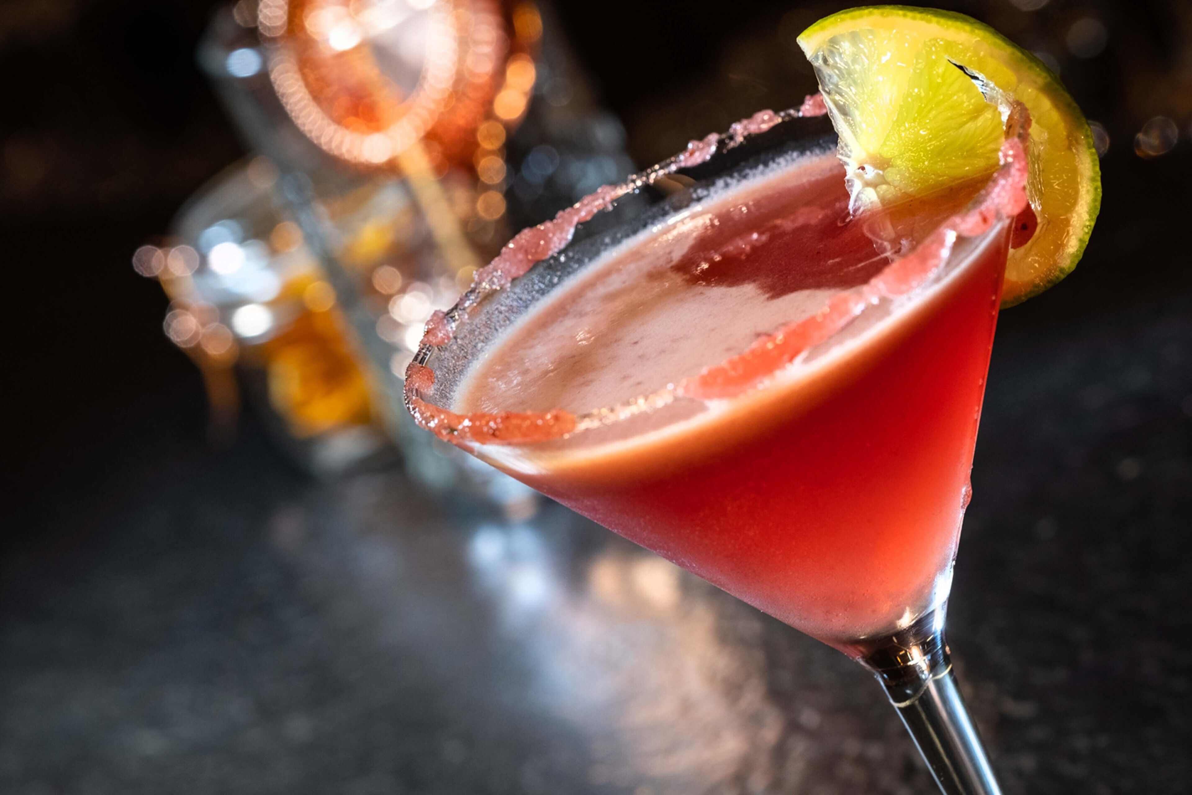 Um cocktail num copo de martini, com a borda salgada e uma fatia de limão.