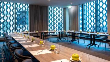 A conference room with a long table set for meetings, equipped with chairs and glassware.