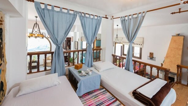 A hotel room with two beds, a balcony, and a view of the outside.