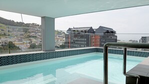 A rooftop infinity pool with a city view, a glass balustrade, and a tiled edge. - Naomi By Stay Amazing (Cape Town)