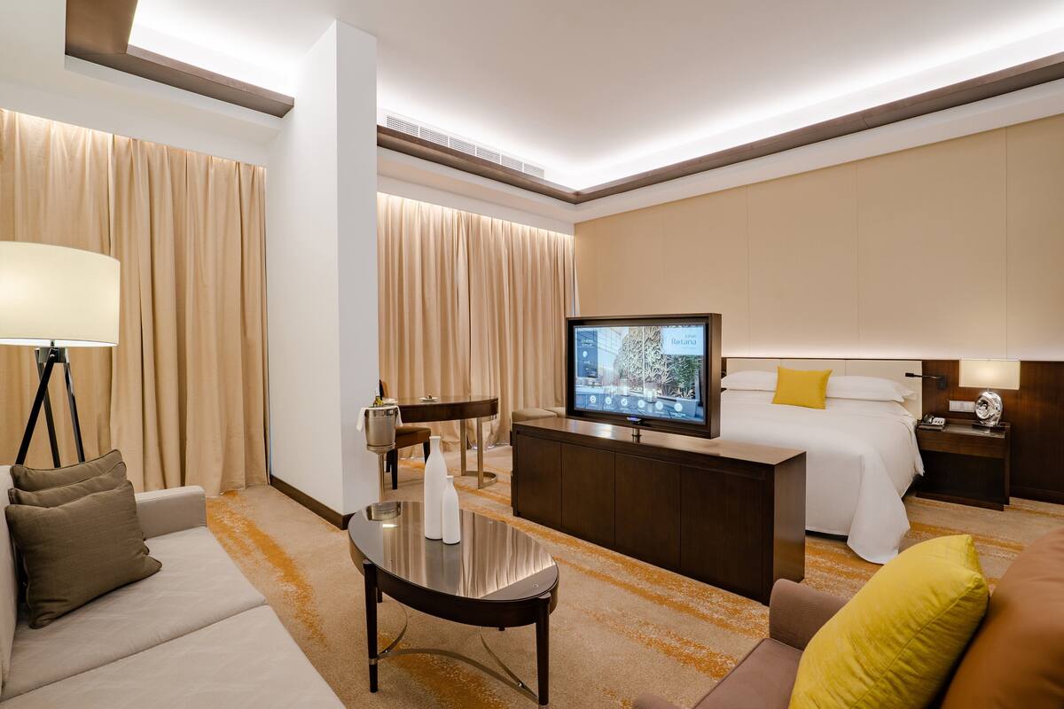 A hotel room with a bed, a TV, a desk, and a sofa.