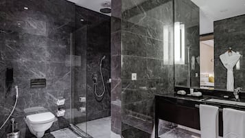 Un baño moderno con ducha de vidrio, inodoro y un espejo grande sobre el lavabo.