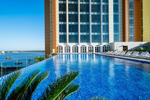 A swimming pool with lounge chairs and a view of a tall building with large windows.