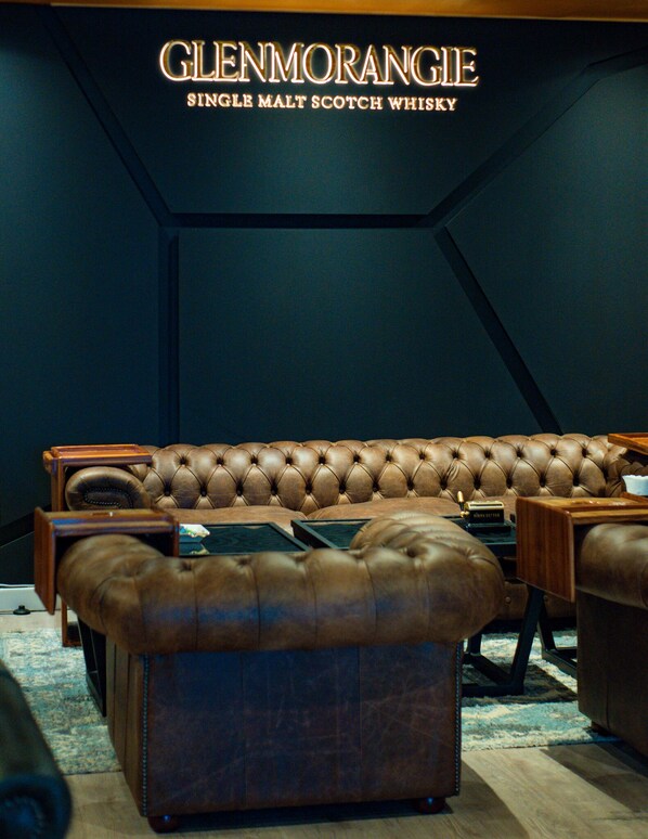 A luxurious leather sofa in a dimly lit room with a sign above reading "GLENMORANGIE SINGLE MALT SCOTCH WHISKY".