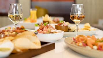 Una mesa de comedor con diferentes platos y dos copas de vino blanco.