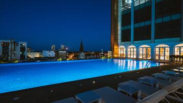 Una piscina al aire libre, sillones reclinables de piscina