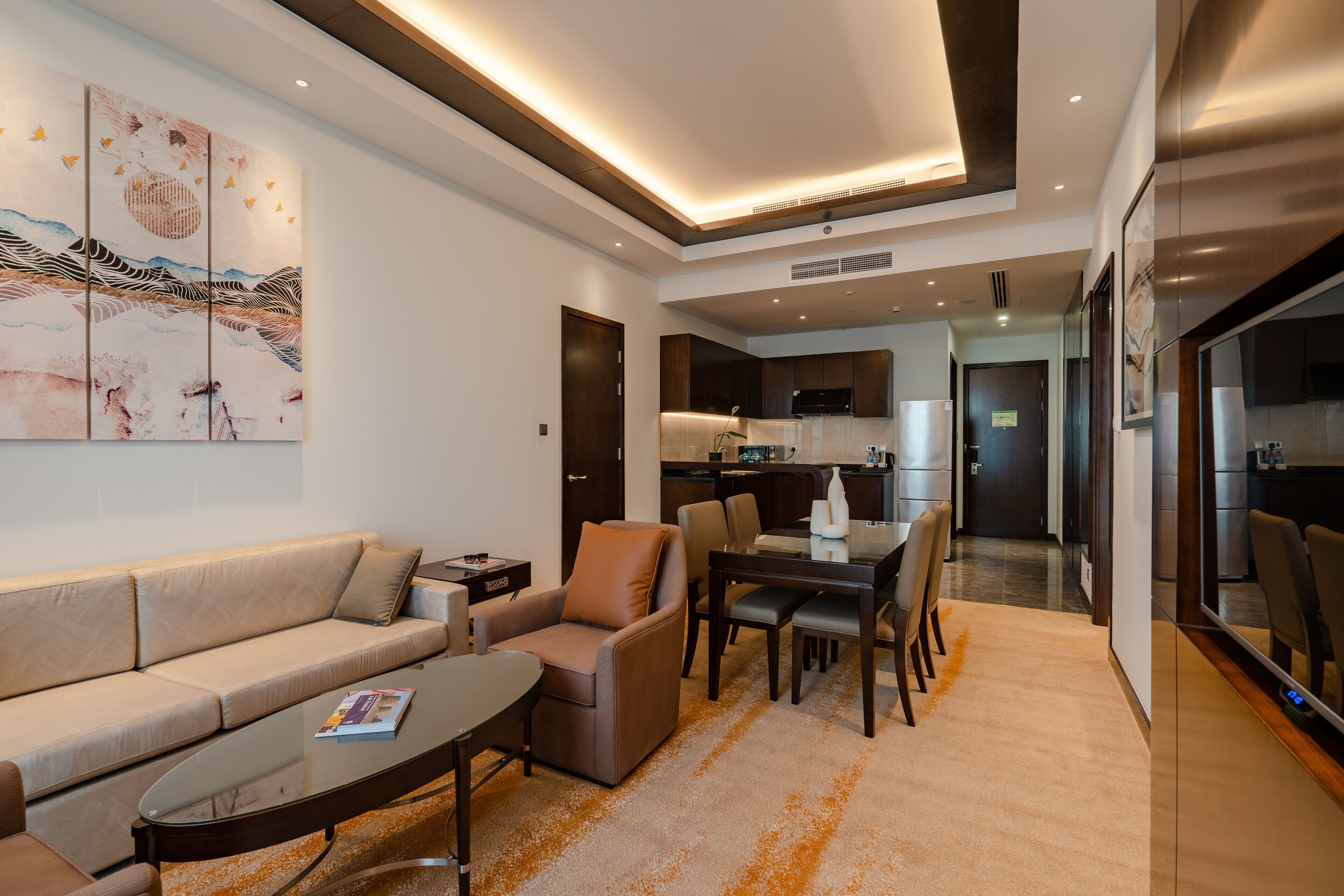 A modern living room with a sofa, armchair, coffee table, and dining area with chairs.
