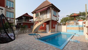 A two-story building with a swimming pool, outdoor furniture, and a balcony. - AG Hotel and Suites (Accra)