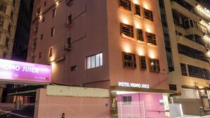 Un hôtel à plusieurs étages, reconnaissable à son enseigne bien visible sur laquelle on peut lire : « HÔTEL NOMO JUICE ».