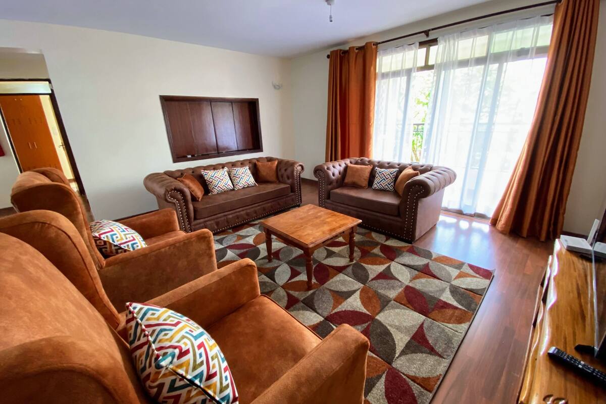 Una sala de estar con dos sofás marrones, una mesa de centro y un televisor en la pared.
