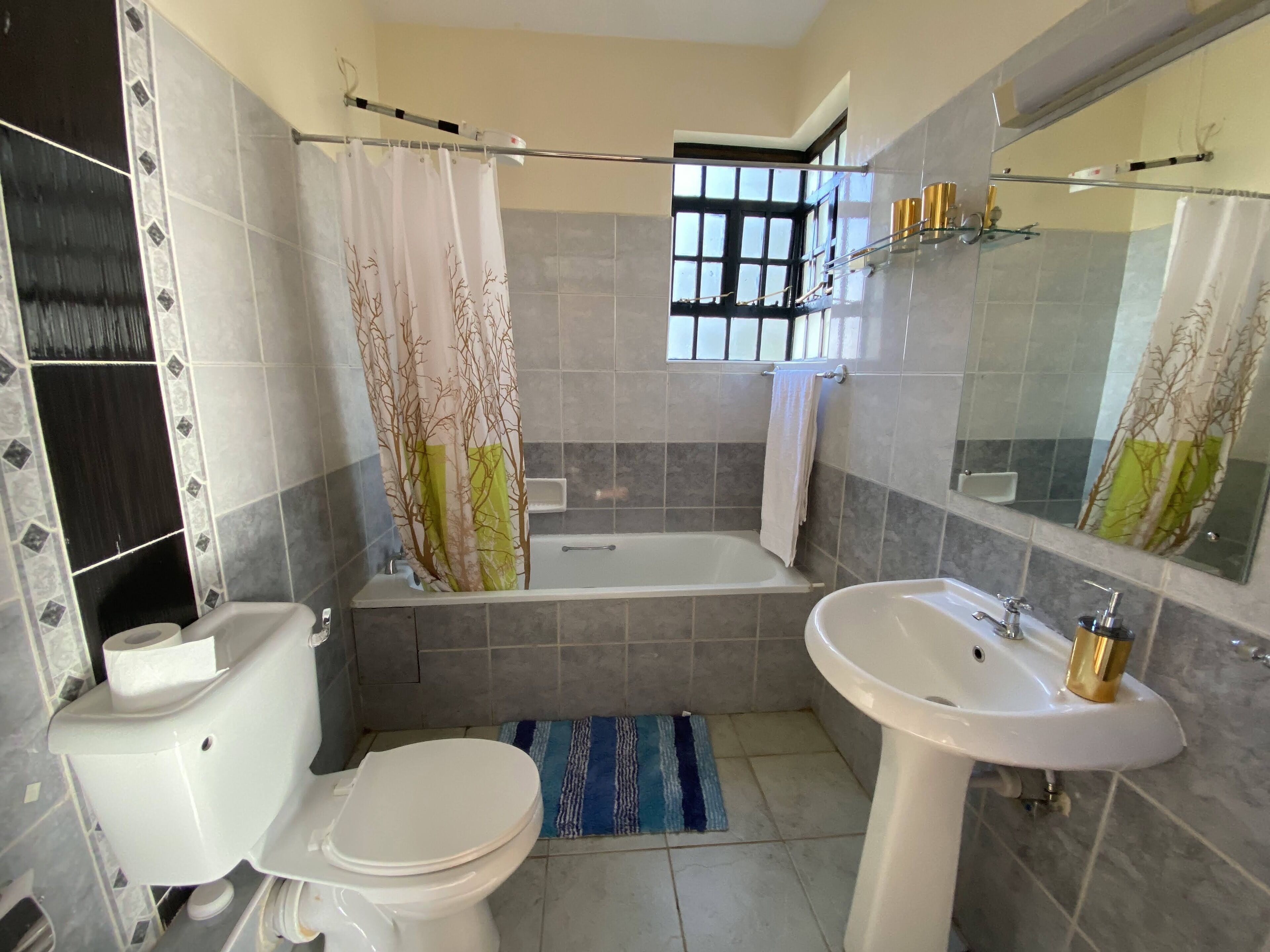 A bathroom with a toilet, sink, bathtub, and a window.