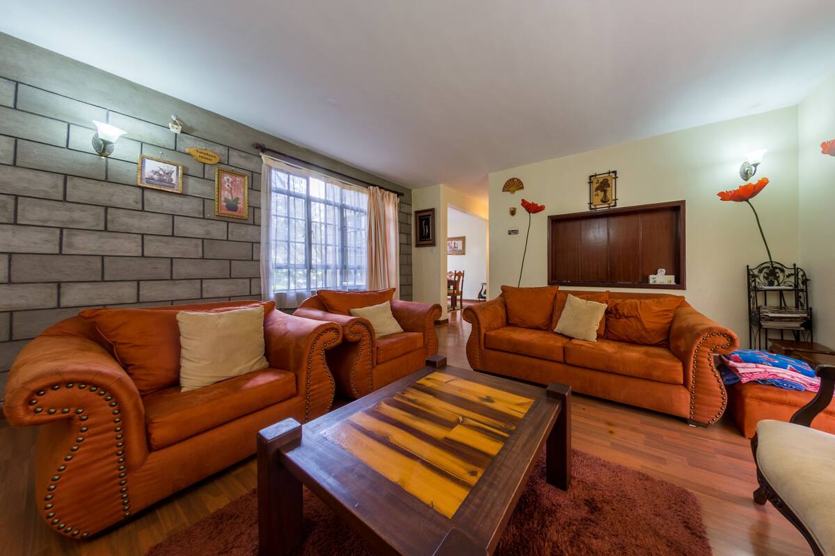 Una sala de estar con dos sofás de cuero, una mesa de centro de madera y una pared de ladrillo.