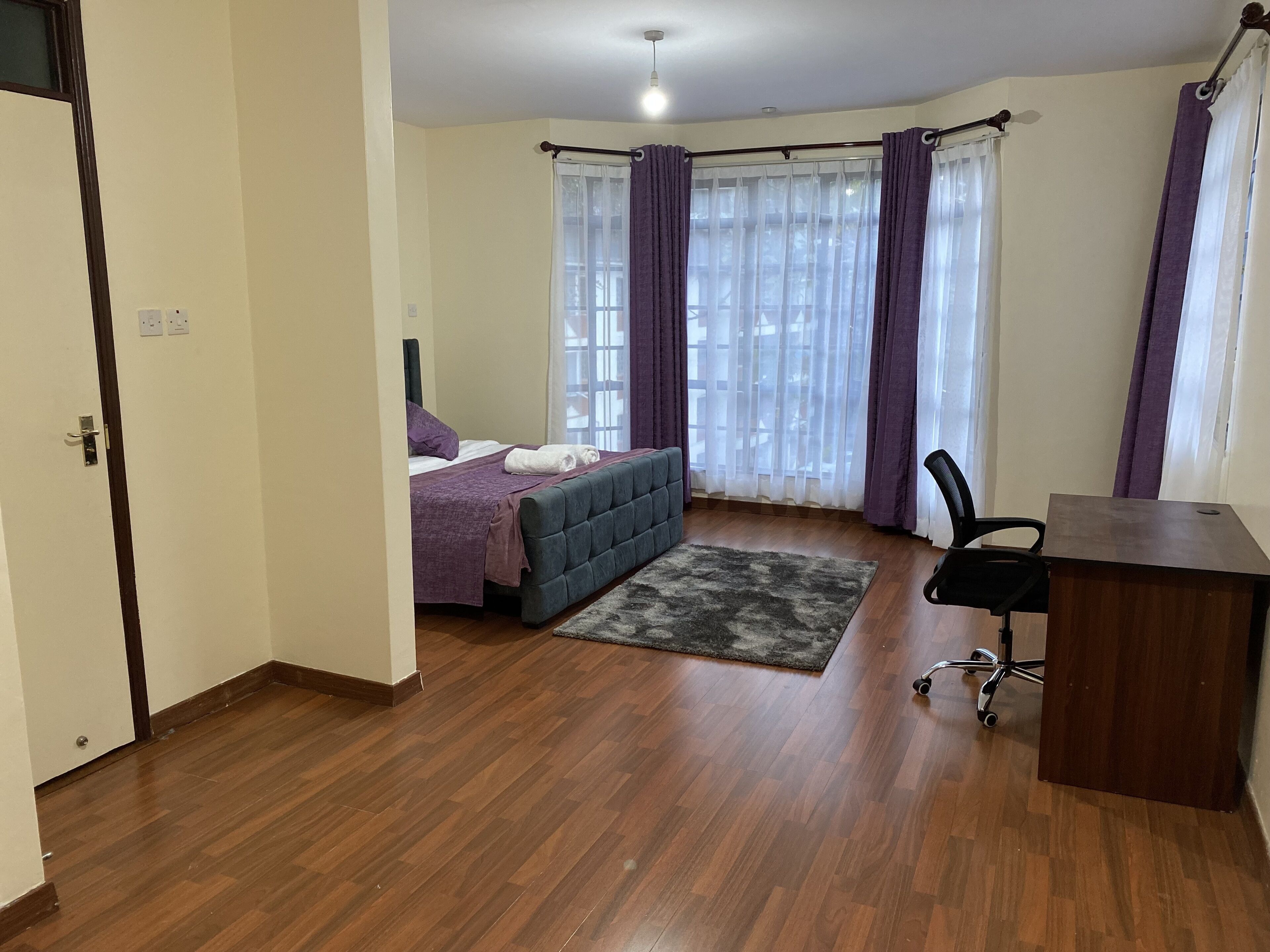Een slaapkamer met een bed, een bureau en een stoel.